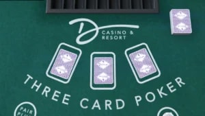 A green Three Card Poker table with three face-down playing cards in player positions and a deck of cards to the side. The table is branded 'D CASINO & RESORT'.